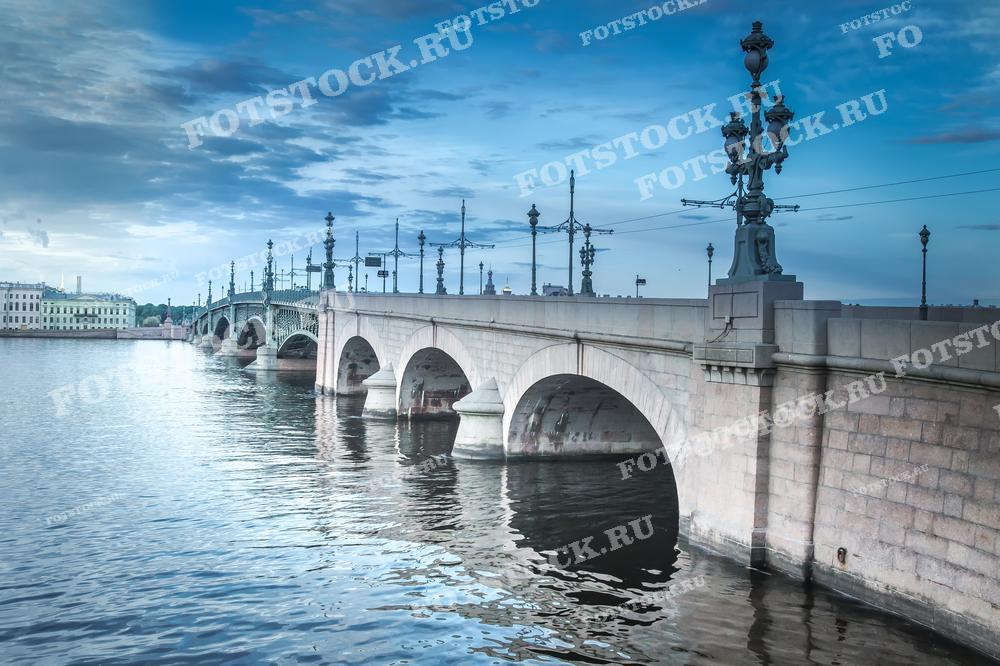 Этот снимок показывает Троицкий мост в Санкт-Петербурге, известный своими элегантными лампами и архитектурной красотой, на фоне утреннего неба. Фотография подойдёт для использования в туристических публикациях, учебных материалах и в качестве декоративного элемента в офисах или домах.